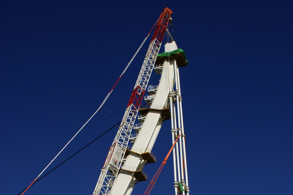Valencia, Spain - June 16, 2008: Workers put huge metal girder towers thanks to a crane during the construction of a bridge.